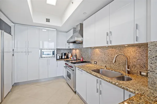 a kitchen with stainless steel appliances granite countertop a sink stove refrigerator and cabinets