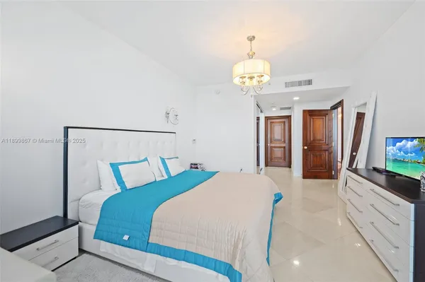 a bedroom with a large bed and a flat tv screen on dresser