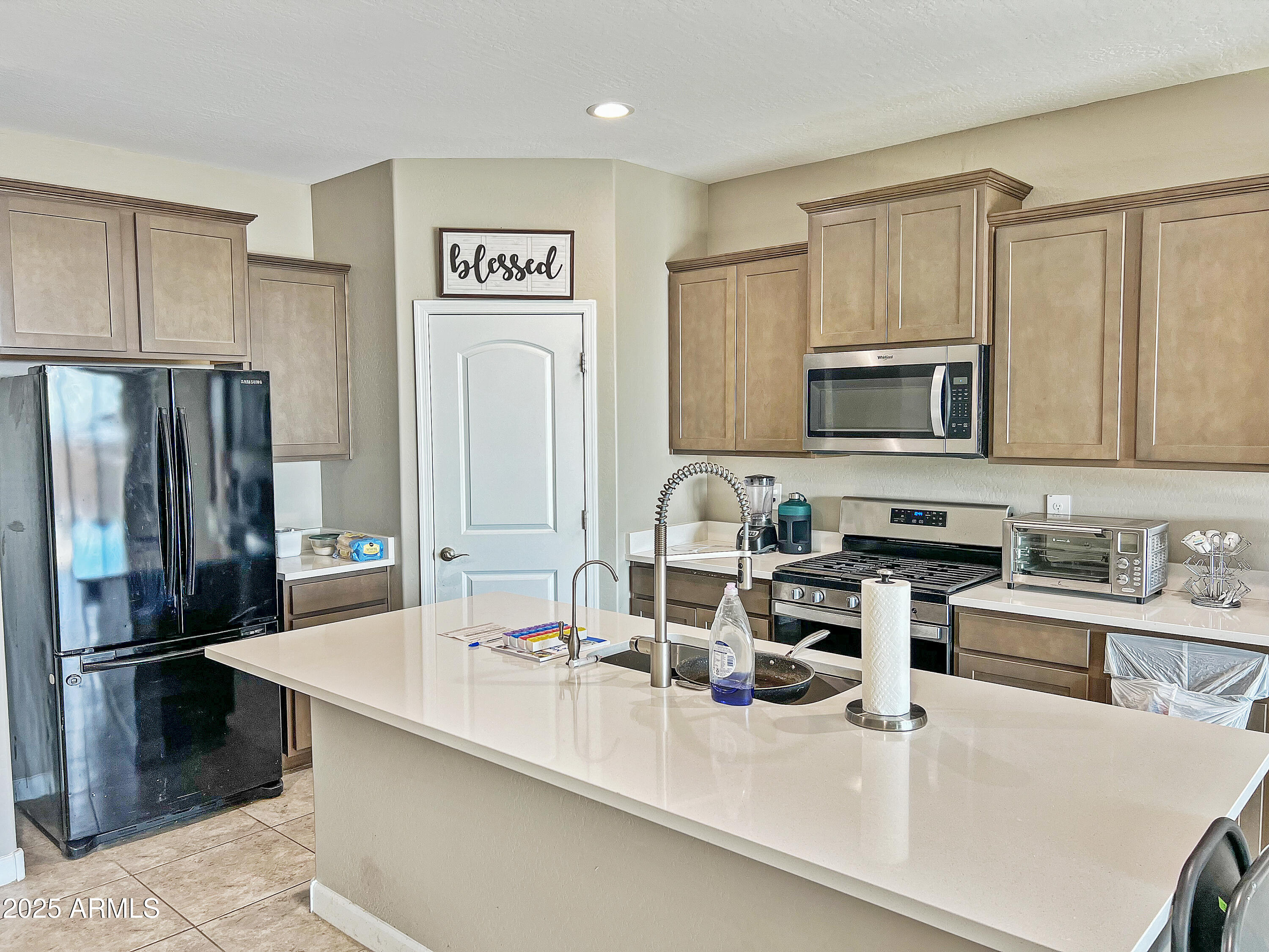 8491 West Springfield Way Florence, AZ 85132 - Photo 10 of 34 a kitchen with stainless steel appliances a sink a stove a microwave a refrigerator a counter space and cabinets
