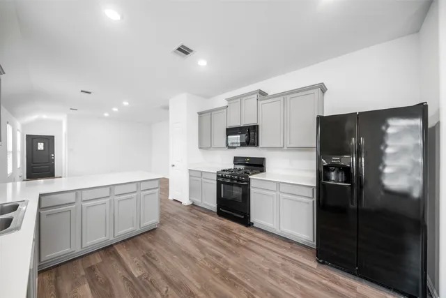 a large kitchen with a center island wooden floor stainless steel appliances and cabinets