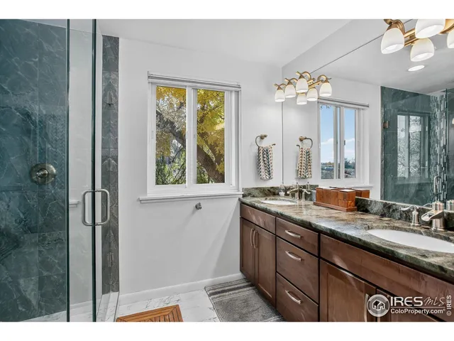 a bathroom with a double vanity sink and mirror with shower
