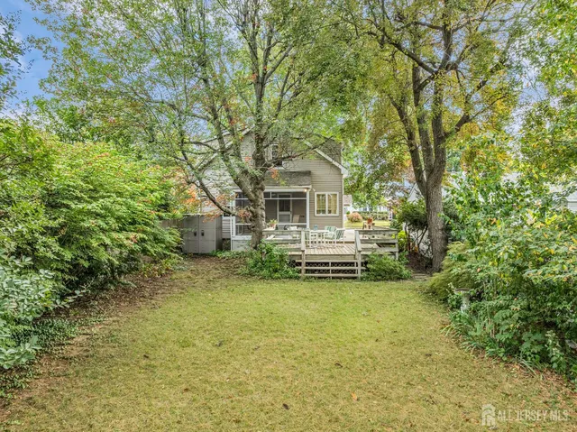a view of a white house next to a yard with potted plants