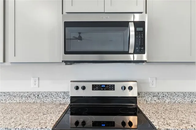 a kitchen with granite countertop stainless steel appliances a sink stove and cabinets