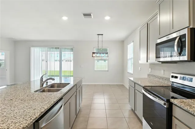 a kitchen with granite countertop white cabinets stainless steel appliances and a window