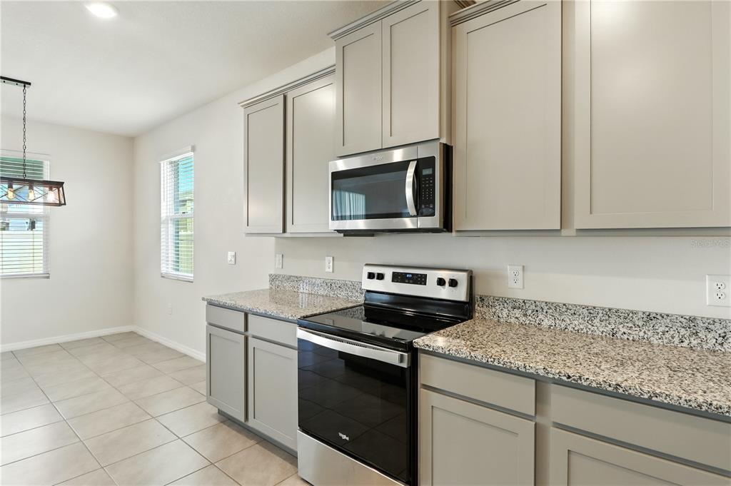 8931 Southwest 49th Circle Ocala, FL 34476 - Photo 32 of 42 a kitchen with granite countertop white cabinets stainless steel appliances and a window