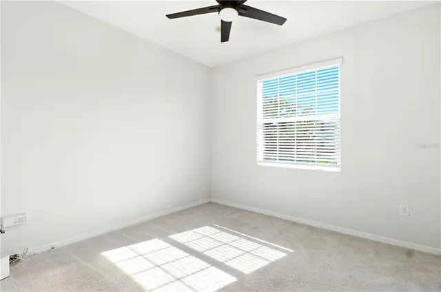 an empty room with ceiling fan and window