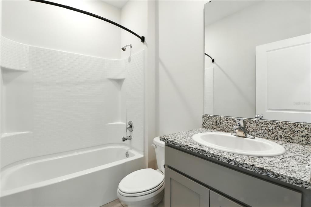 8931 Southwest 49th Circle Ocala, FL 34476 - Photo 36 of 42 a bathroom with a granite countertop sink a toilet and shower