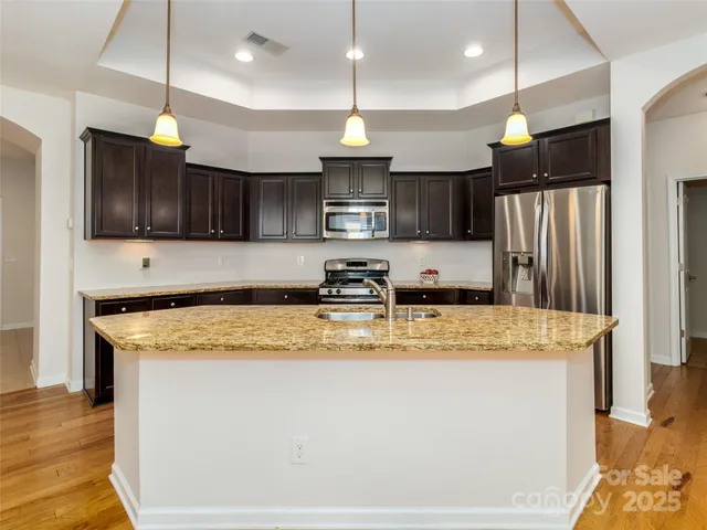 a kitchen with stainless steel appliances granite countertop a stove a sink and a microwave