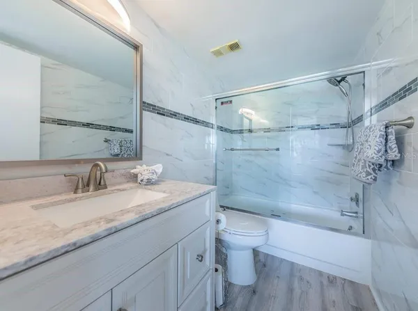 a bathroom with a granite countertop sink a toilet and shower
