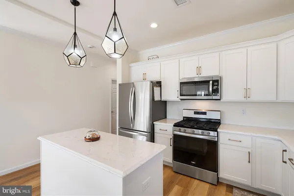 a kitchen that has a kitchen island wooden cabinets and stainless steel appliances