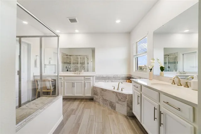 a large white bathroom with a large mirror vanity and a bathtub