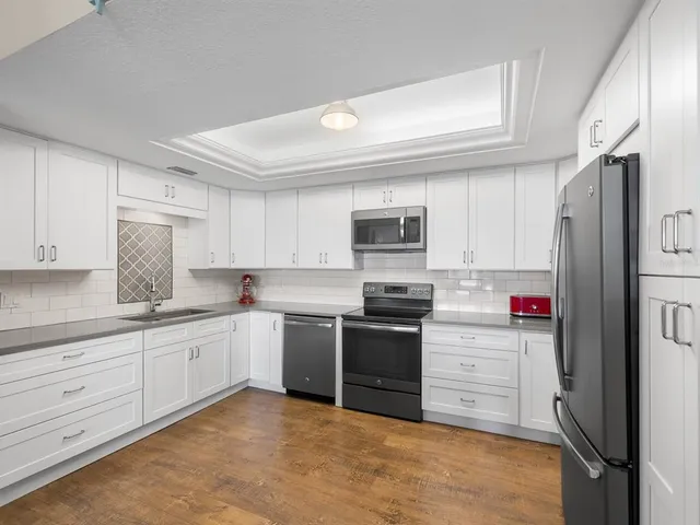 a kitchen with granite countertop a refrigerator stove top oven and sink