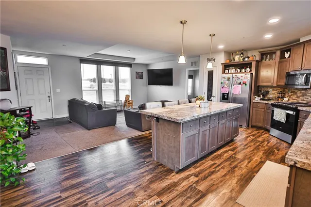 a large kitchen with stainless steel appliances kitchen island granite countertop a large stove a sink dishwasher and a fireplace with wooden floor