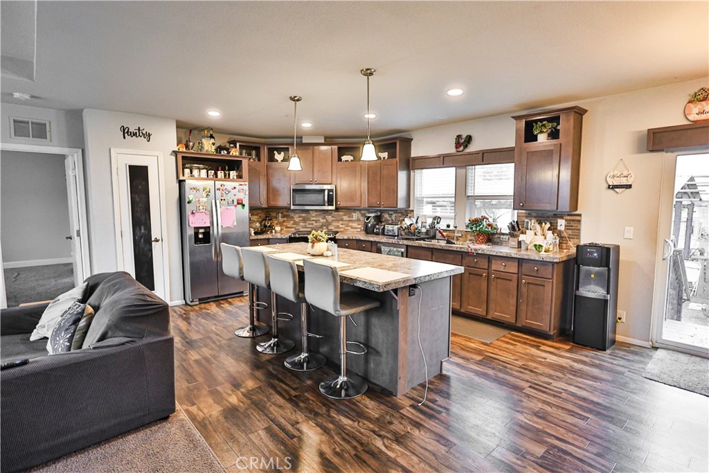 4210 Osborn Road Flournoy, CA 96021 - Photo 21 of 50 a kitchen with stainless steel appliances granite countertop a stove top oven a refrigerator a sink and dishwasher with wooden floor