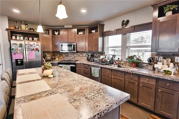 a kitchen with stainless steel appliances kitchen island granite countertop a sink stove and refrigerator