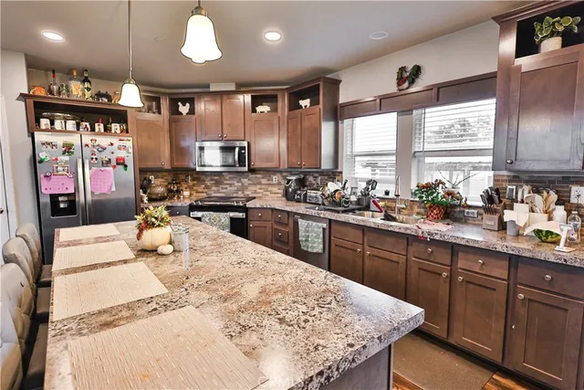 a kitchen with stainless steel appliances kitchen island granite countertop a sink stove and refrigerator