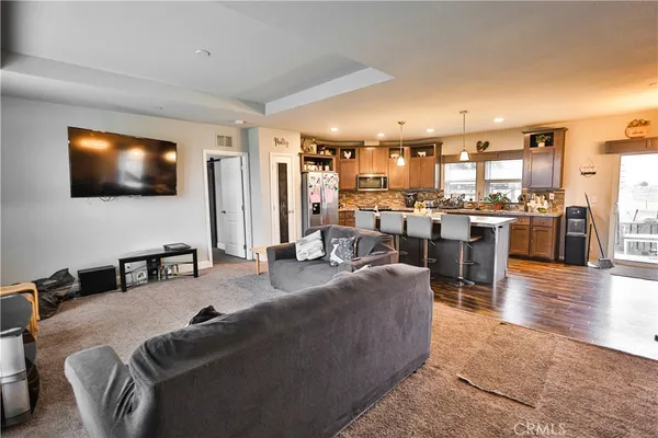 a living room with stainless steel appliances furniture and a flat screen tv