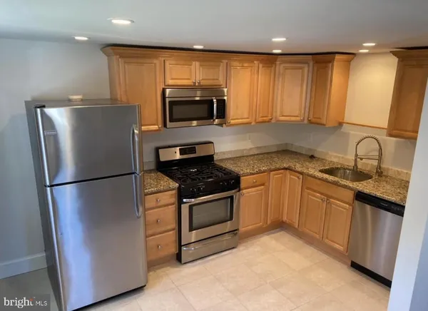 a kitchen with stainless steel appliances granite countertop a refrigerator sink and stove