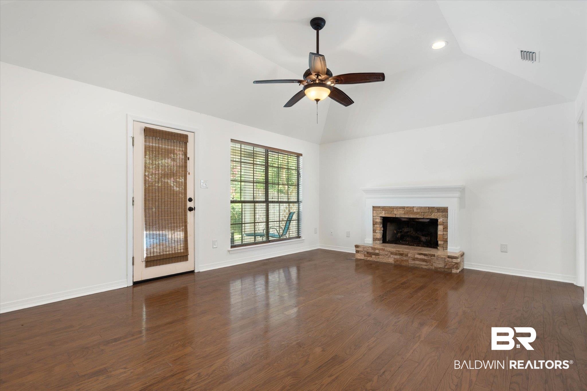 3032 Autumn Ridge Drive West Mobile, AL 36695 - Photo 8 of 20 Unfurnished living room with vaulted ceiling, a stone fireplace, ceiling fan, wood finished floors, and recessed lighting
