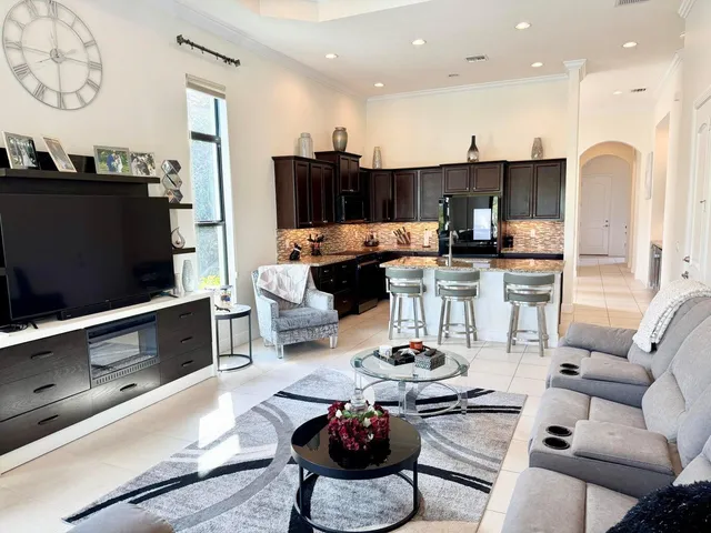 a living room with furniture a flat screen tv and kitchen view