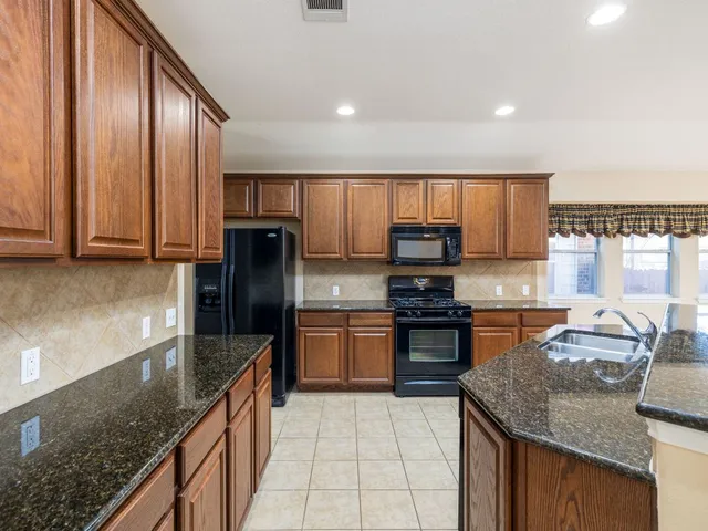 a kitchen with stainless steel appliances granite countertop wooden cabinets a stove a sink and a granite counter top