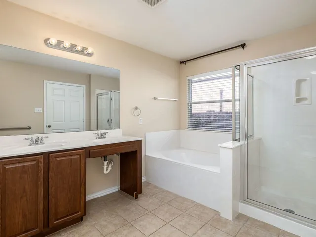 a spacious bathroom with a bathtub a double vanity sink and mirror