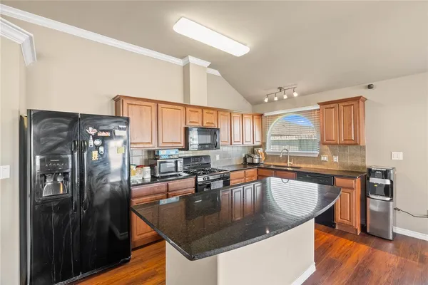 a kitchen with stainless steel appliances granite countertop sink stove top oven and refrigerator