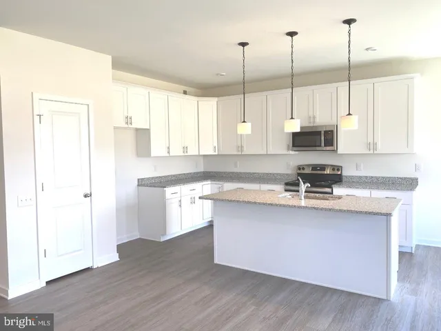 a kitchen with stainless steel appliances granite countertop a sink a stove and a wooden floor