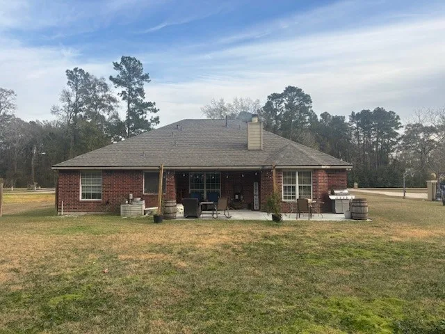 a front view of a house with yard and trees in the background