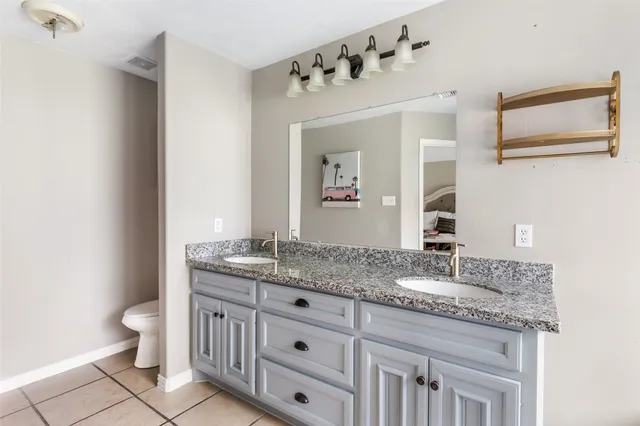a bathroom with a granite countertop sink toilet and mirror