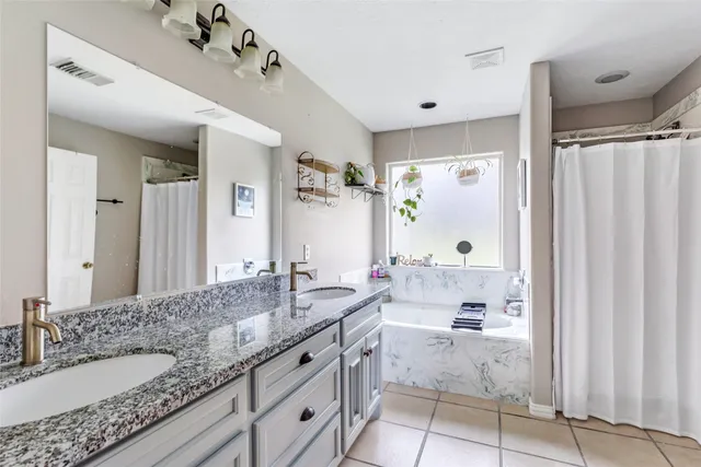 a spacious bathroom with a granite countertop sink a mirror a and a bathtub