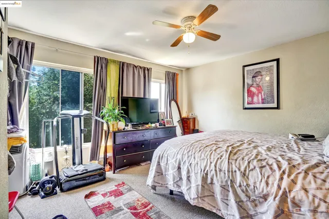 a bedroom with a bed a dresser and a large window