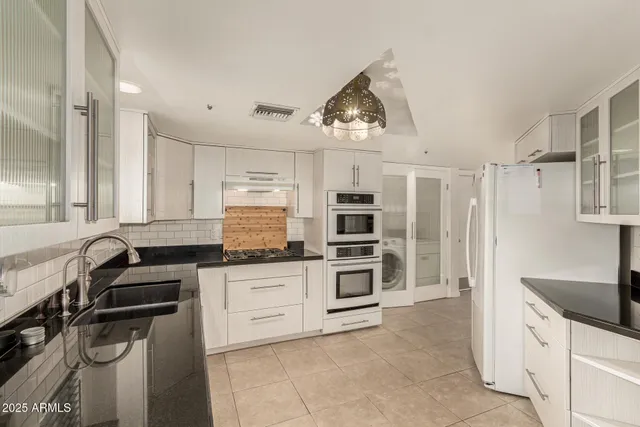 a kitchen with granite countertop a stove a sink and a refrigerator