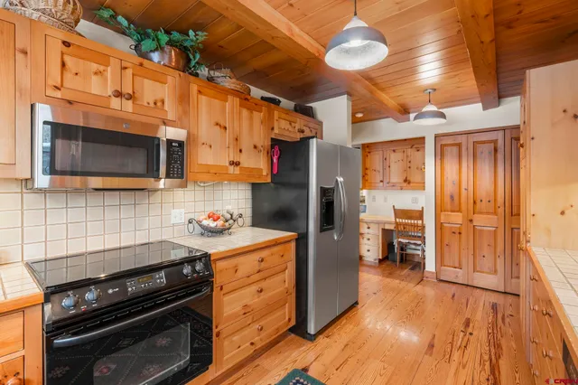 a kitchen with stainless steel appliances a stove a refrigerator and a wooden floor