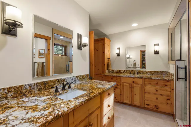 a bathroom with a granite countertop double vanity sink and a mirror