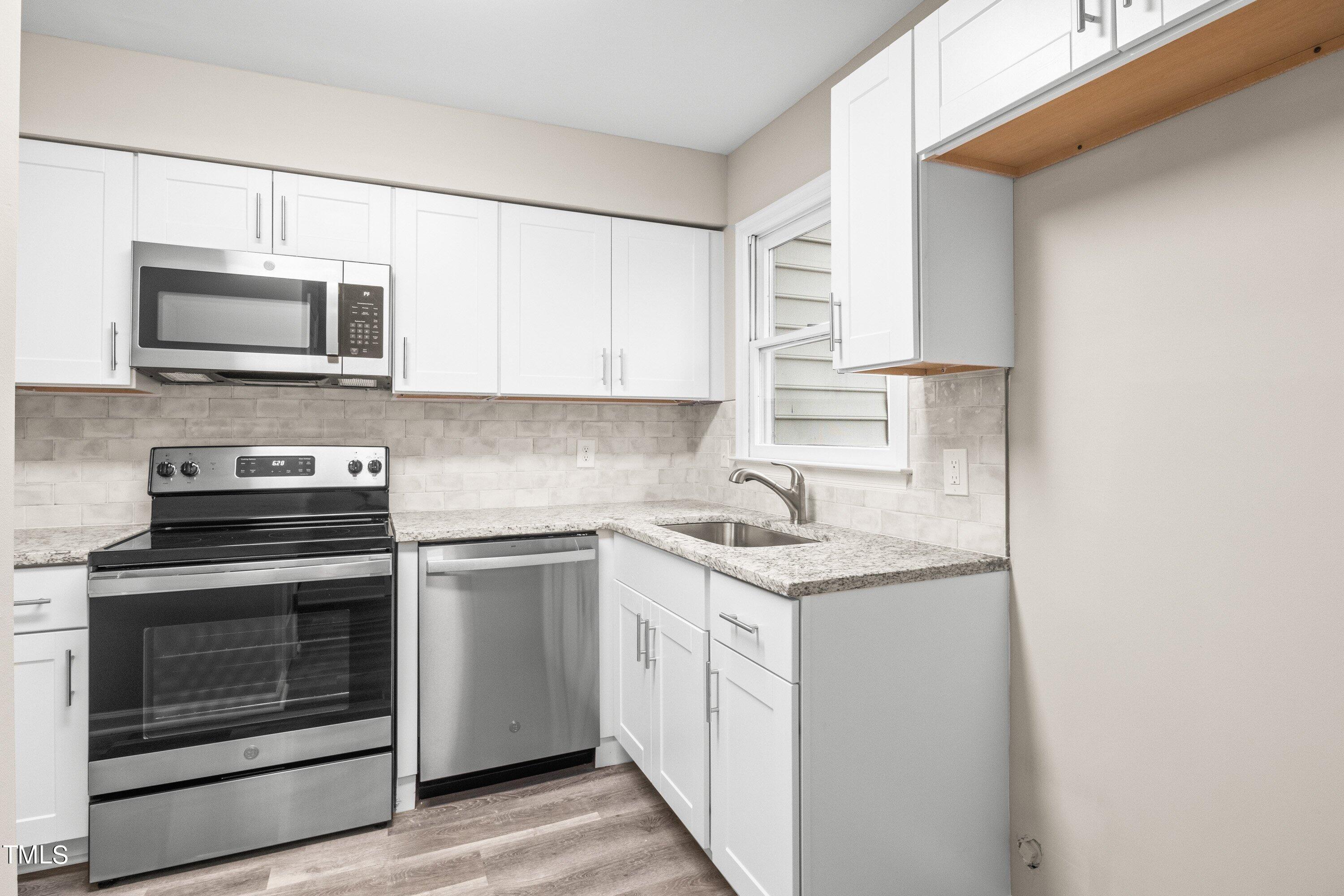 4440 Roller Court Raleigh, NC 27604 - Photo 20 of 38 a kitchen with stainless steel appliances granite countertop white cabinets stove a sink and dishwasher