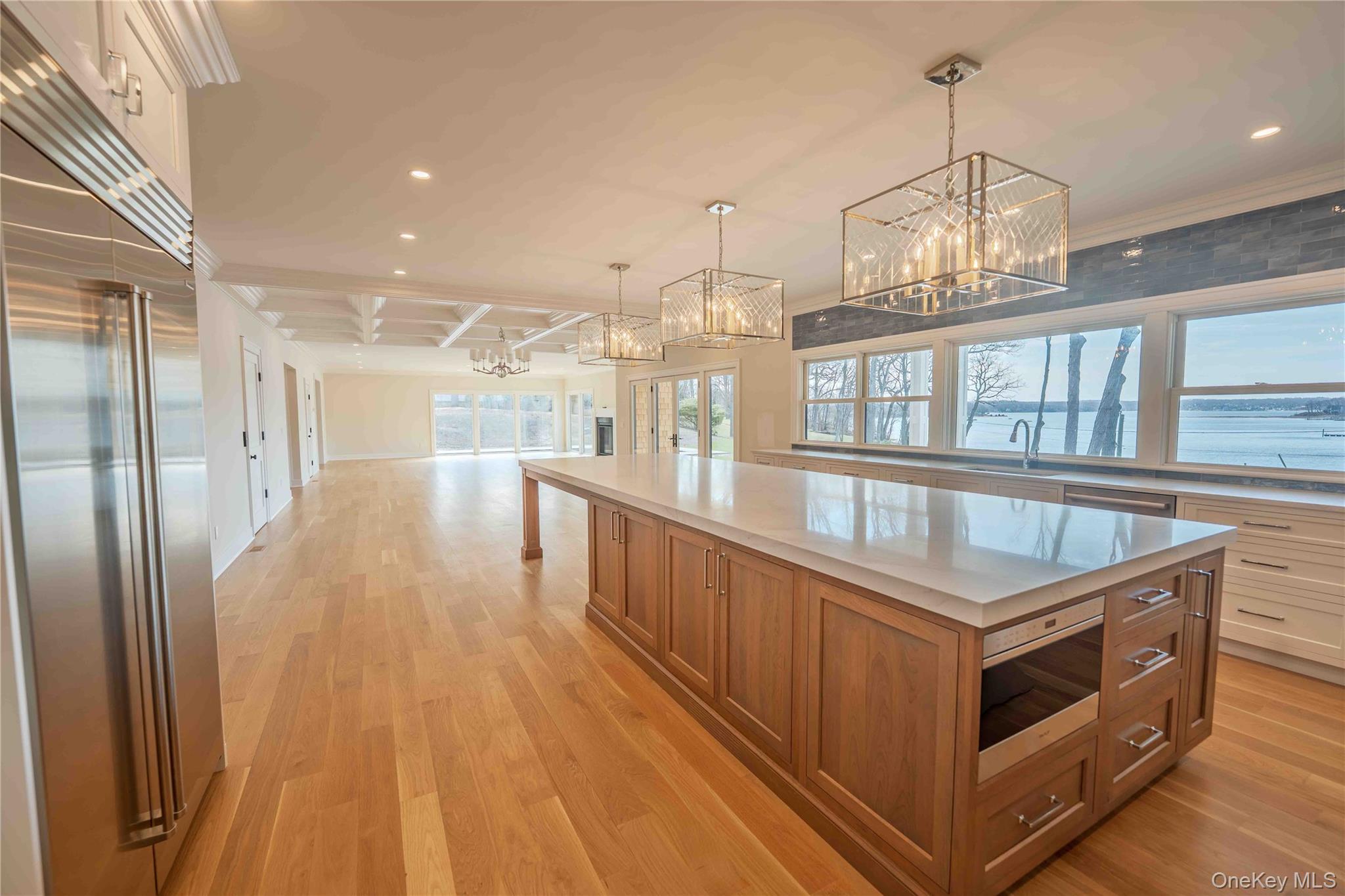 106 Cove Road Asharoken, NY 11768 - Photo 44 of 46 Dual tone kitchen with built in appliances, open floor plan, light wood-style flooring, a chandelier, and a spacious island