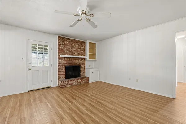 an empty room with wooden floor a fireplace and windows