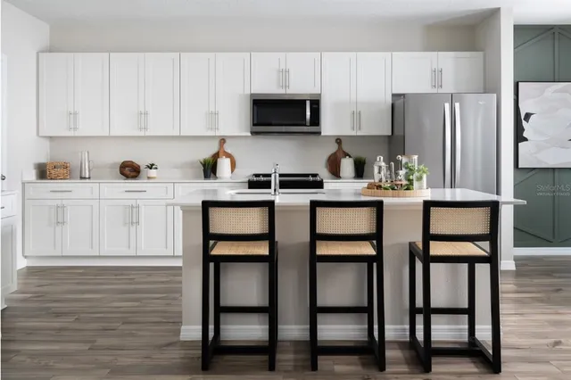 a kitchen with stainless steel appliances granite countertop a stove a refrigerator a white table and chairs