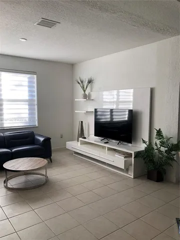 a living room with furniture a flat screen tv and a window