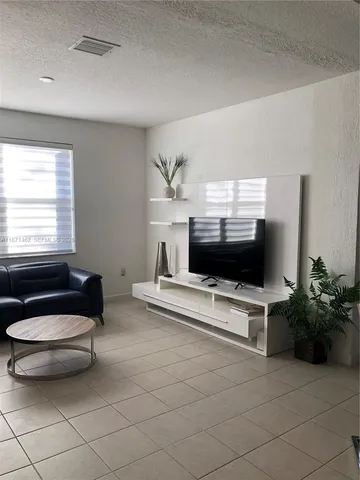a living room with furniture a flat screen tv and a window