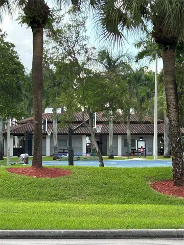 a front view of a building with garden and trees