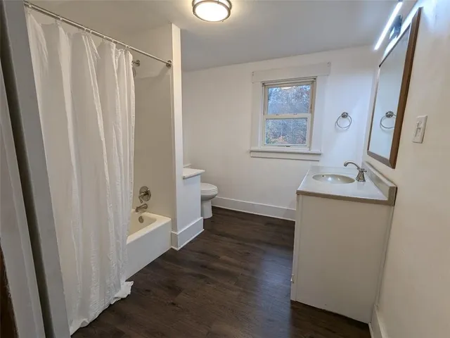 a view of a hallway with wooden floor and a cabinet