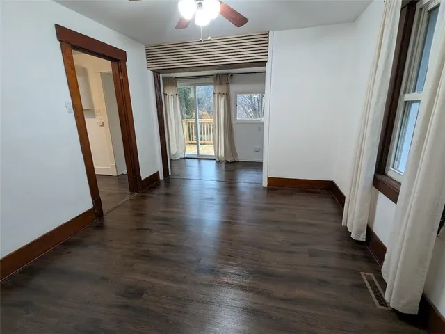 an empty room with wooden floor and a ceiling fan