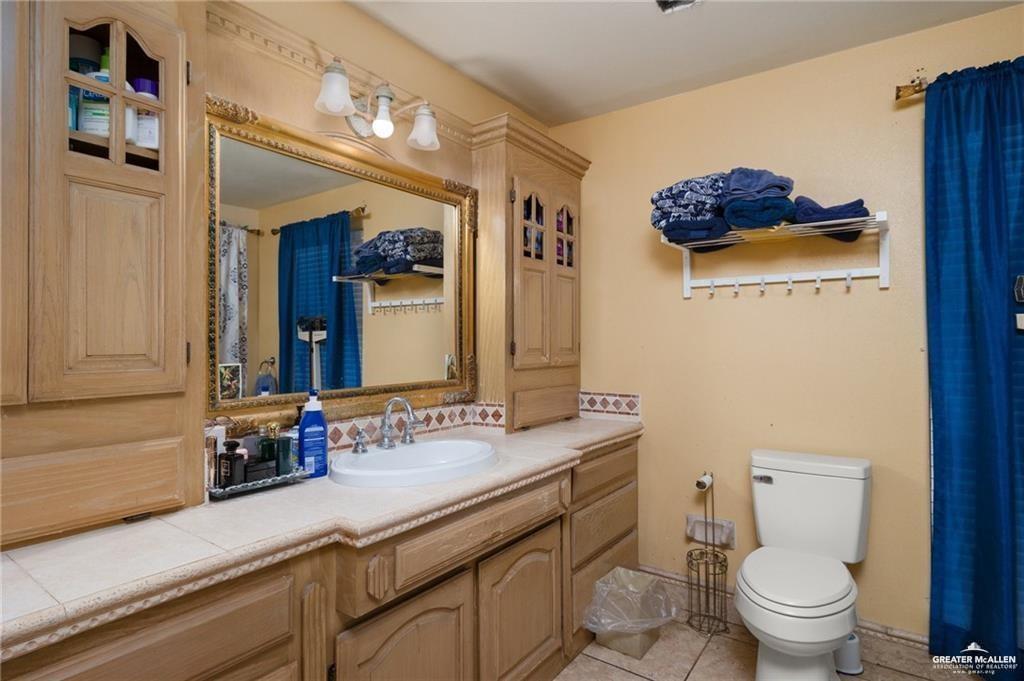 4523 South Tower Road Edinburg, TX 78542 - Photo 22 of 32 a bathroom with a sink a toilet and a mirror