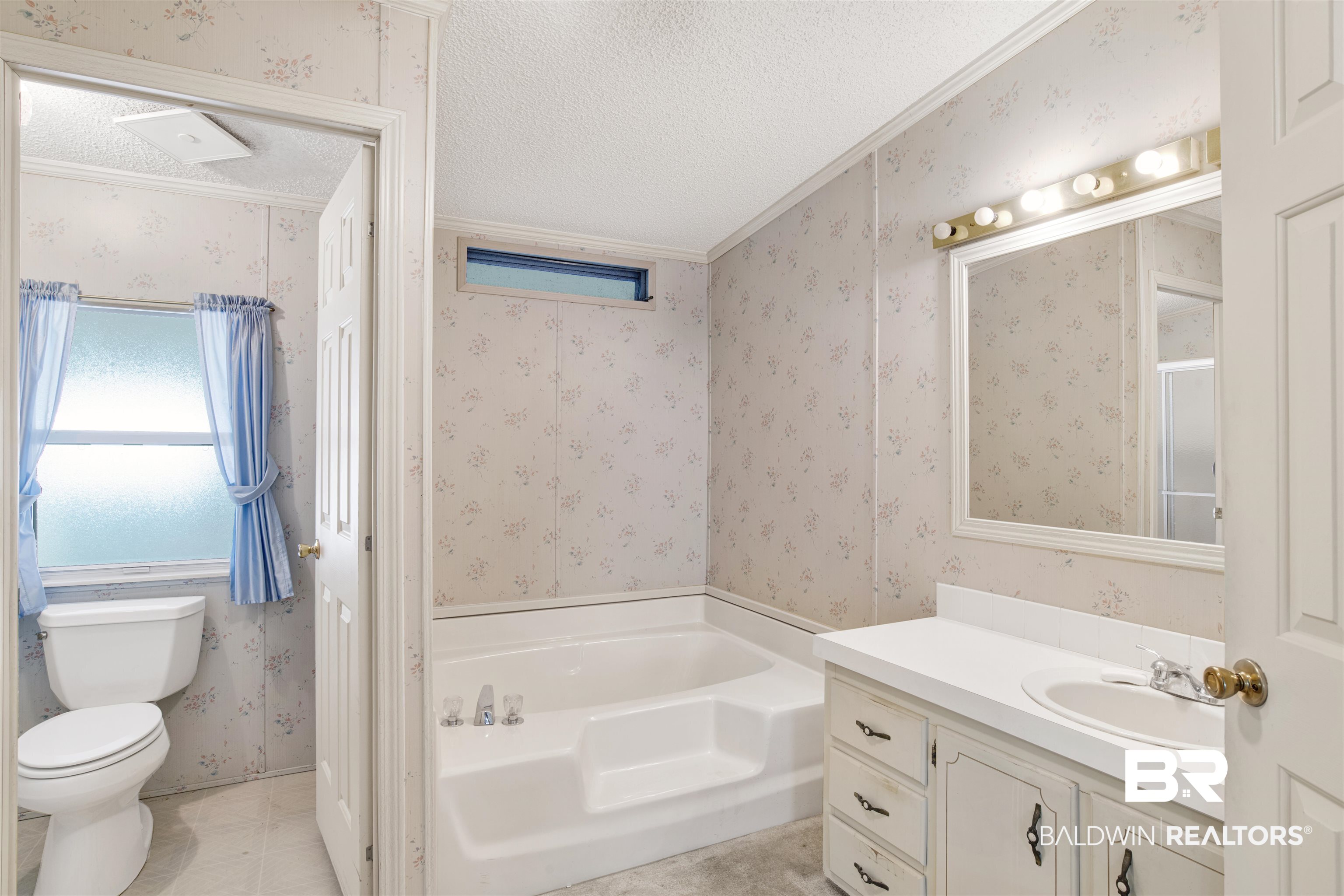 1216 Ridgewood Drive Lillian, AL 36549 - Photo 12 of 29 Bathroom with wallpapered walls, a bath, vanity, a textured ceiling, and ornamental molding