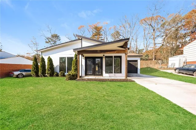 a view of a white house with a big yard and potted plants
