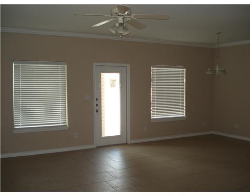15209 South Padre Island Drive, Unit 104 Corpus Christi, TX 78418 - Photo 2 of 6 an empty room with wooden floor chandelier fan and windows