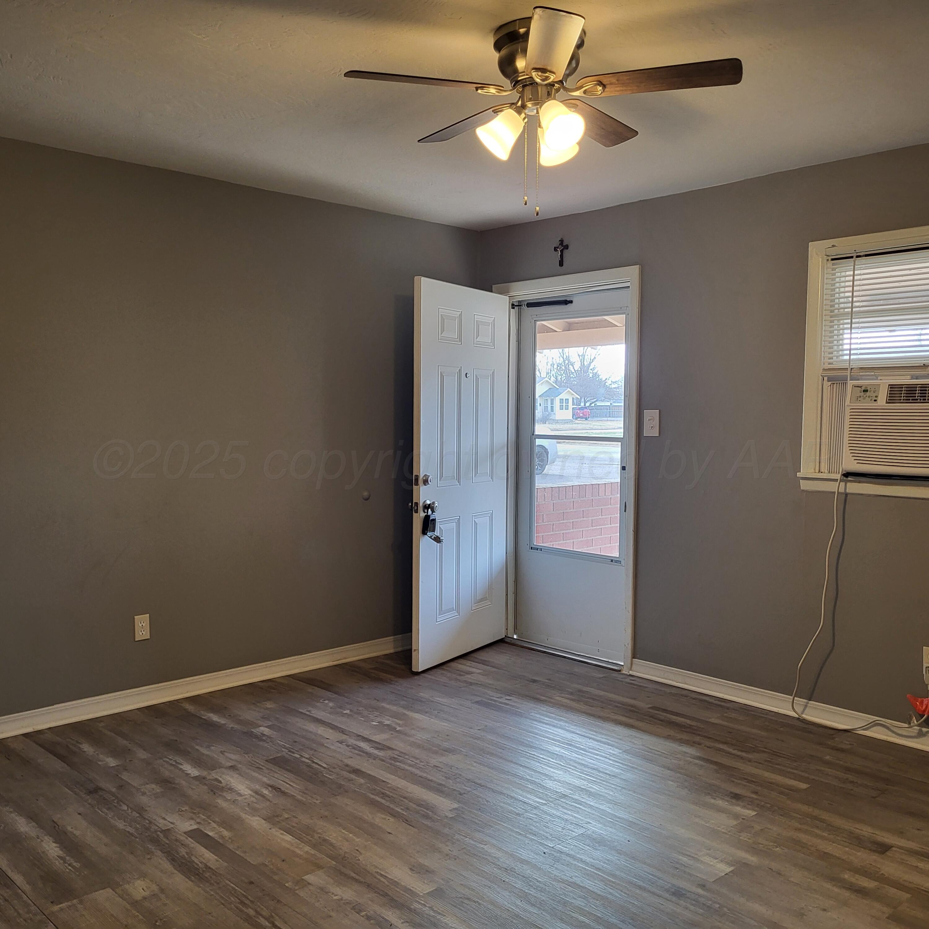 609 16th Street, Unit 4 Canyon, TX 79015 - Photo 3 of 9 an empty room with wooden floor chandelier fan and windows