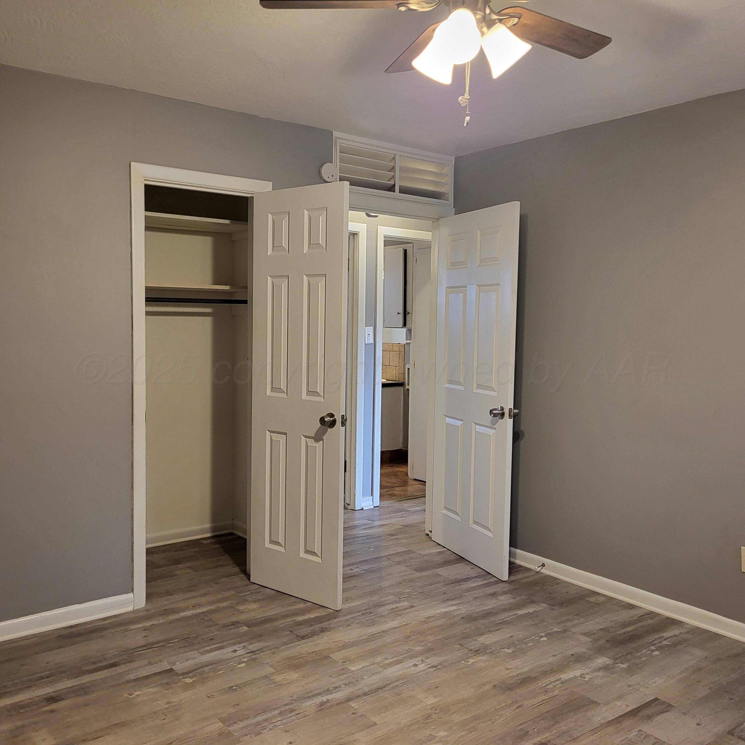 609 16th Street, Unit 4 Canyon, TX 79015 - Photo 5 of 9 an empty room with wooden floor cabinet and a bathroom